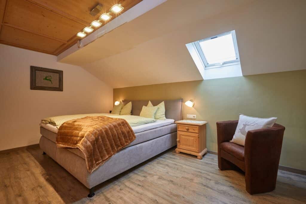 Ferienwohnung Gams_Schlafzimmer mit Doppelbett und Sessel_Gästehaus Isartal in Krün