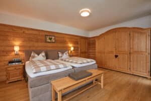 Ferienwohnung Rehbock_Gemütliches Schlafzimmer mit viel Holz und braunem Boxspringbett_Gästehaus Isarwinkel in Krün